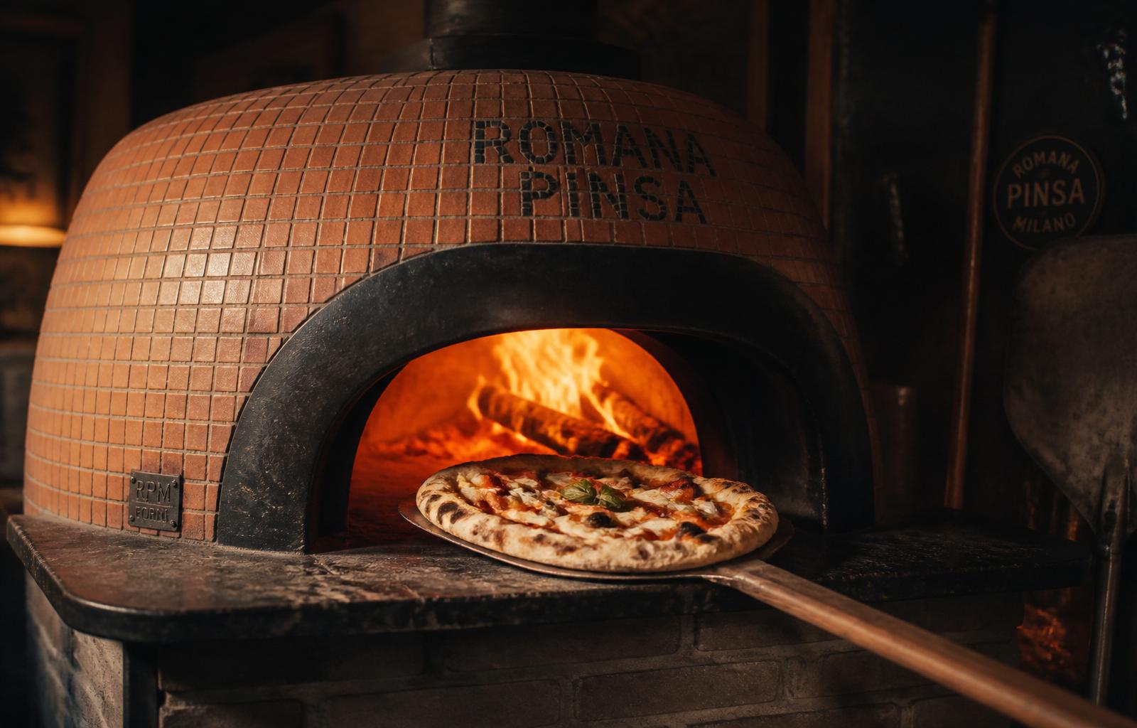 Il forno a legna di Nuovo Ciottolo con la fiamma viva e una pizza appena sfornata